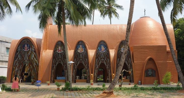 Modern church with stained glass windows and palm trees.