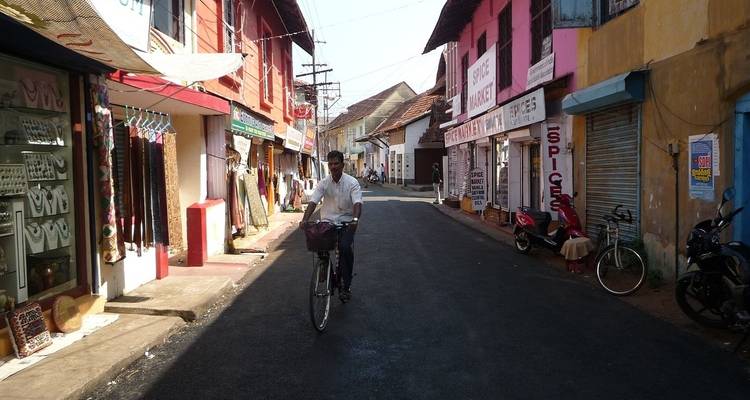 Man riding a bicycle down a narrow, colorful street.