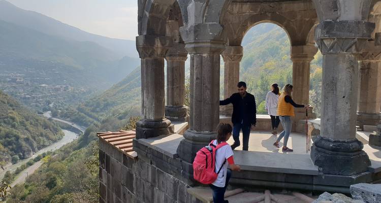 Menschen erkunden eine alte Struktur mit Blick ins Tal.