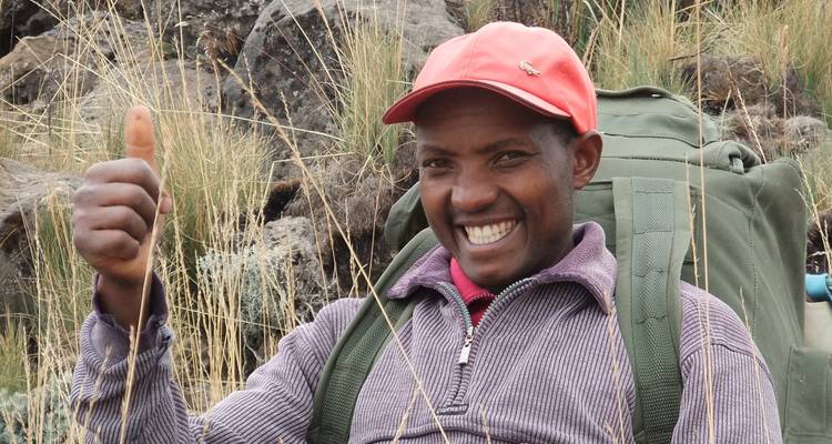 Persoon poseert met duim omhoog op een wandelpad.