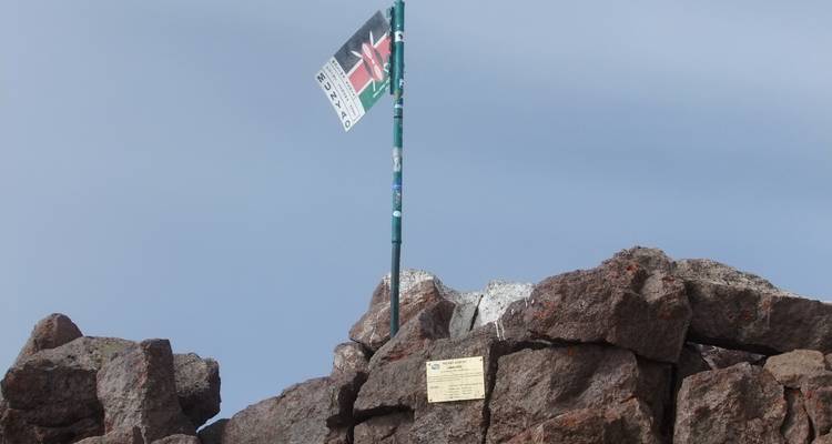 Keniaanse vlag bovenop een rotsachtige bergtop.