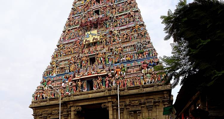 Ein großer Tempelturm mit detaillierten Schnitzereien und einem bewölkten Himmel.