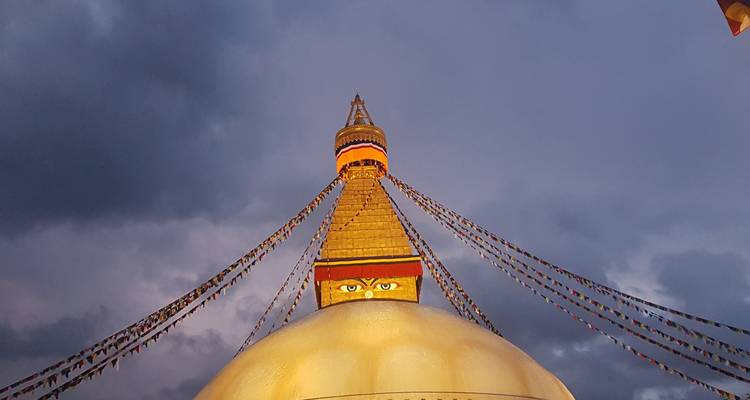 Close-up van een stupa met gebedsvlaggen en stormachtige lucht.