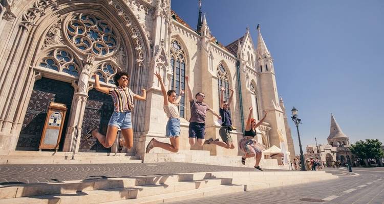 Grupo de personas saltando frente a un edificio histórico.