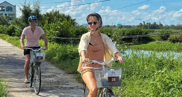 Dos personas en bicicleta por un sendero soleado con vegetación alrededor