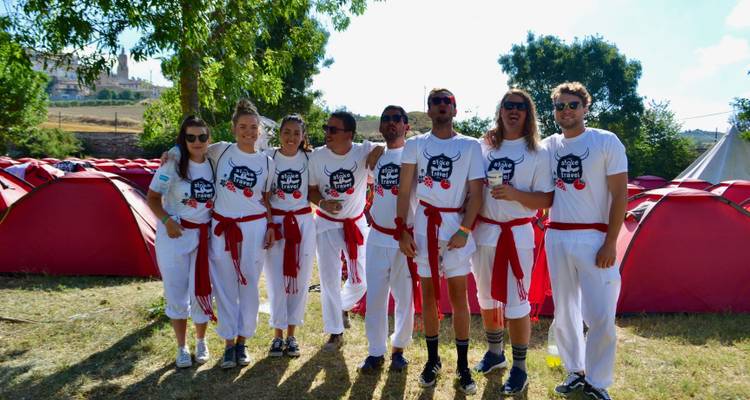 Un groupe de personnes habillées pour l'événement 'Course des Taureaux' posant devant des tentes.