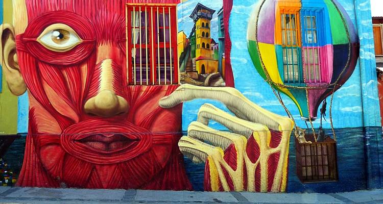 Un vibrante mural callejero que muestra una cara abstracta, una torre y un globo aerostático.