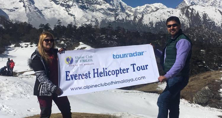 Two people holding a tour banner in a snowy mountain setting.