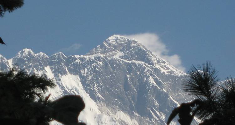 Pico del Himalaya cubierto de nieve que se eleva abruptamente contra un cielo azul despejado.