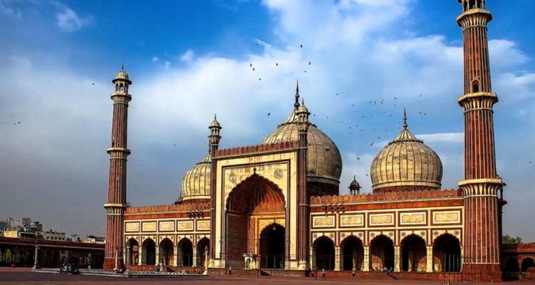 Een grootse moskee met koepels en minaretten tegen een blauwe hemel.