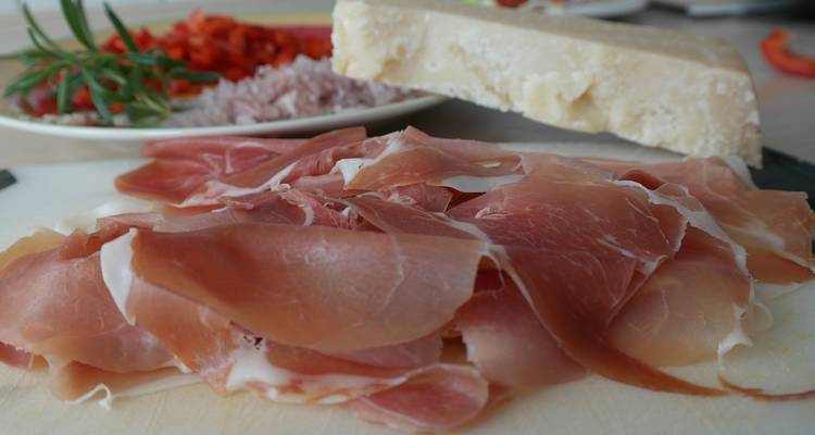 Close-up of prosciutto and parmesan cheese with other ingredients.