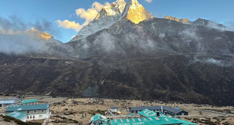 Settlement with buildings at the base of dramatic mountains during sunset.