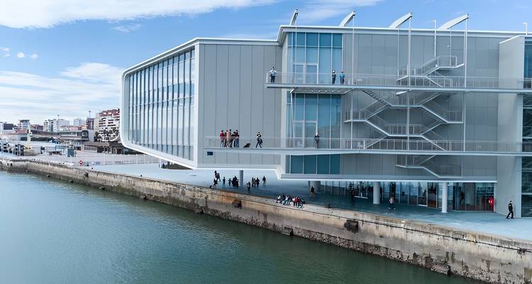 Edificio moderno a lo largo de un malecón con gente caminando.