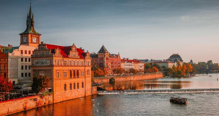 Gouden avondlicht over de Moldau en historische gebouwen langs de rivier in Praag.