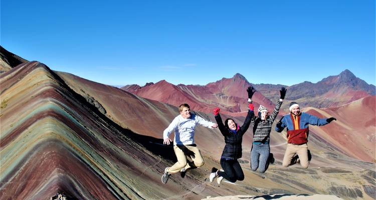 Groep mensen die van vreugde springen voor de Rainbow Mountain.