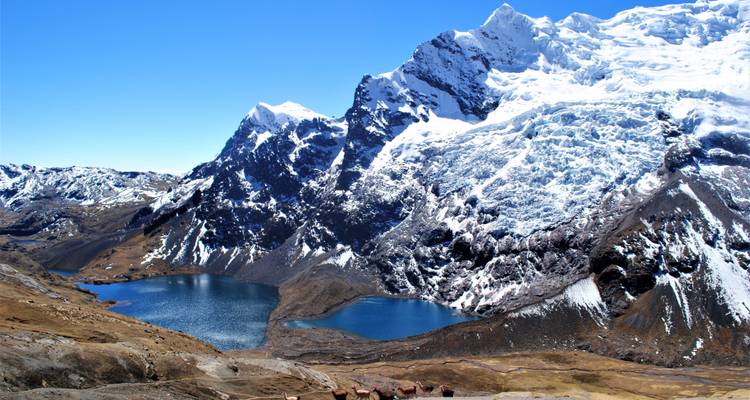 Besneeuwde bergen rondom twee turquoise meren.