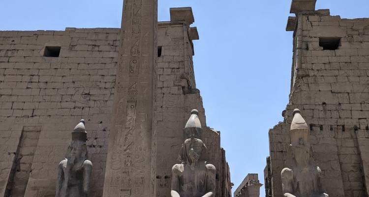 Ingang van een oud-Egyptische tempel geflankeerd door standbeelden en een obelisk.