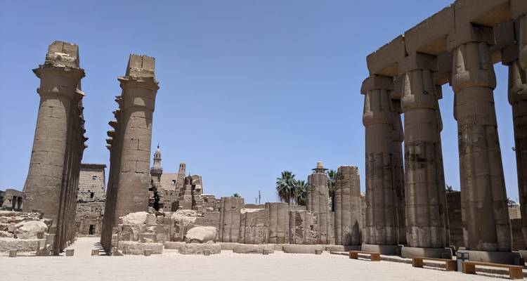 Open binnenplaats van een Egyptische tempel met hoge zuilen en blauwe lucht.