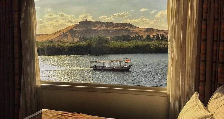 Een schilderachtig uitzicht vanuit een raam dat uitkijkt over een rivier met een boot en heuvels.