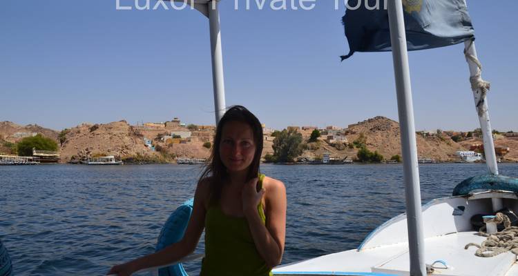 Person on a boat with a view of the river and distant village.