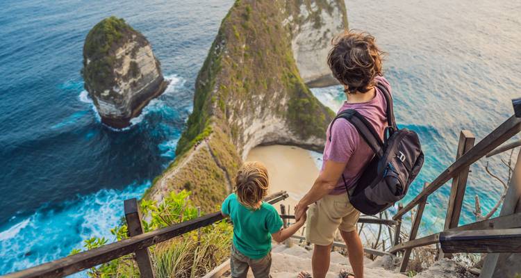 Parent et enfant contemplant une formation rocheuse pittoresque et une baie.