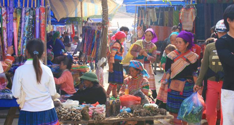 Belebter lokaler Markt mit bunten Kleidern und Stoffen in der Auslage.