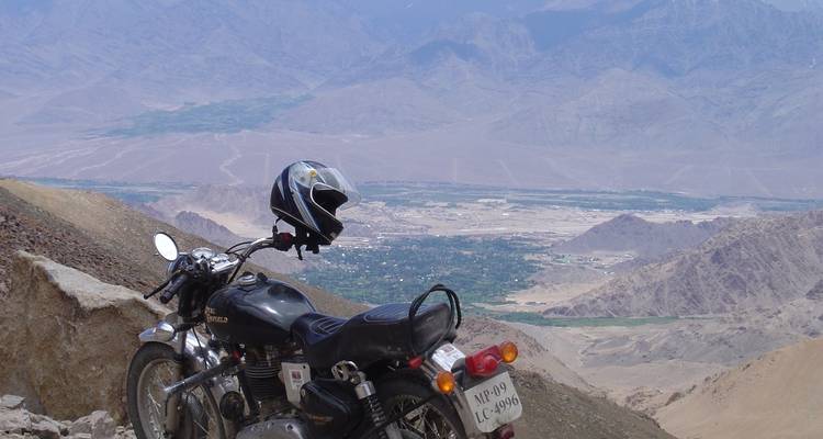 Motocicleta estacionada con vista a montañas y valles.