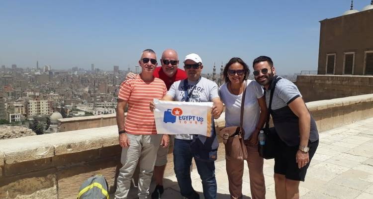 Eine Gruppe von Touristen, die mit einem Reiseführer vor einer Stadtskyline posieren.