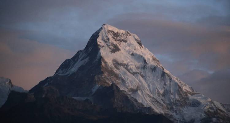 Sonnenbeschienener Berggipfel vor einem Abendhimmel.