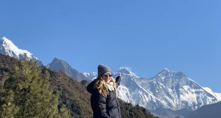 Person pointing towards a snow-capped mountain range in the distance.