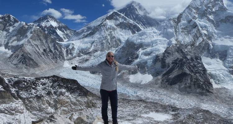 Personne debout les bras étendus devant des montagnes enneigées.