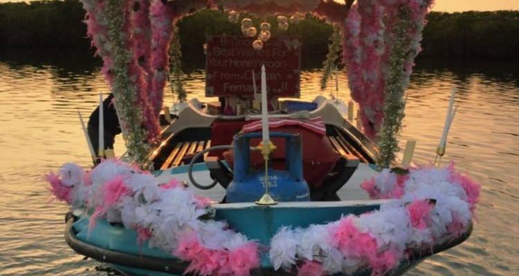 Vue arrière d'un bateau orné de fleurs au crépuscule avec des reflets chaleureux du coucher de soleil sur l'eau.