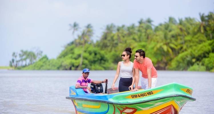 Drie mensen op een kleurrijke boot in een tropische omgeving.