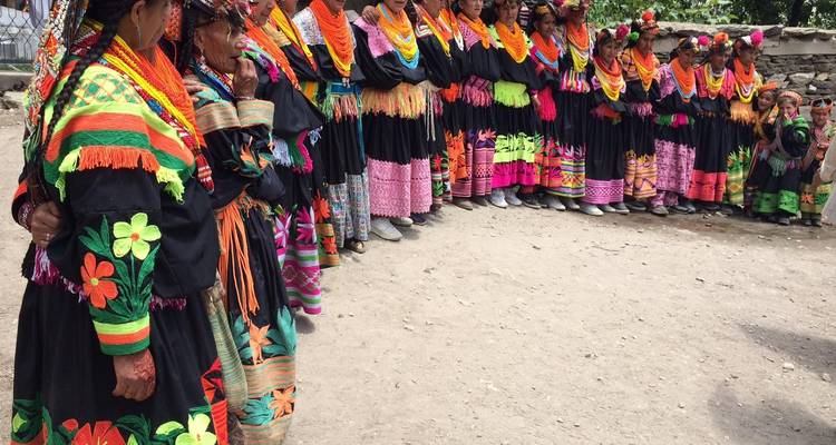 A long line of people in traditional dress standing outside.