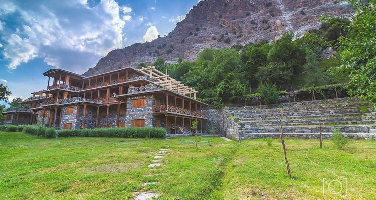 A rustic wooden hotel with the mountains behind.