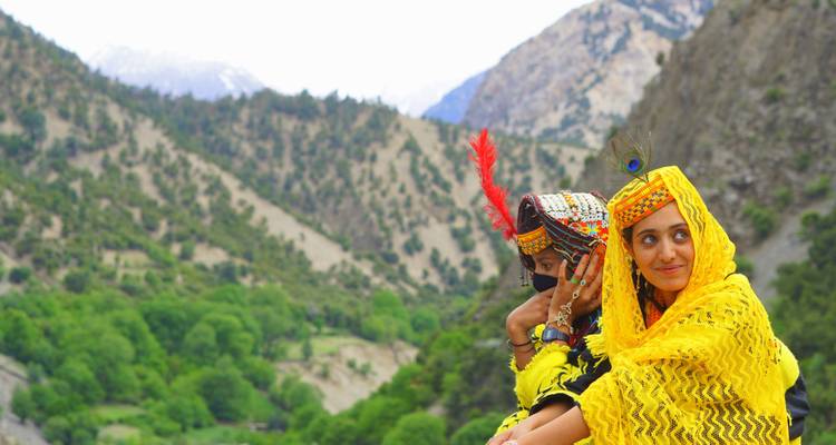 Women in vibrant traditional attire in a hilly landscape.