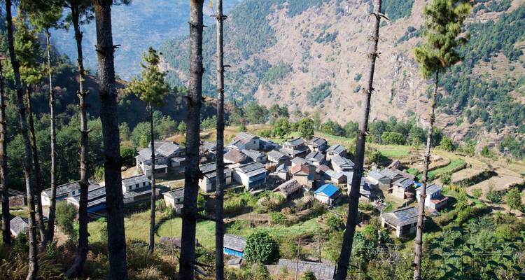 Luftaufnahme eines Dorfes, umgeben von Hügeln und Wäldern.