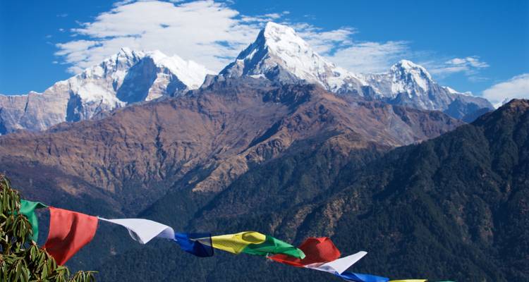 Verschneite Berge mit bunten Gebetsfahnen im Vordergrund.