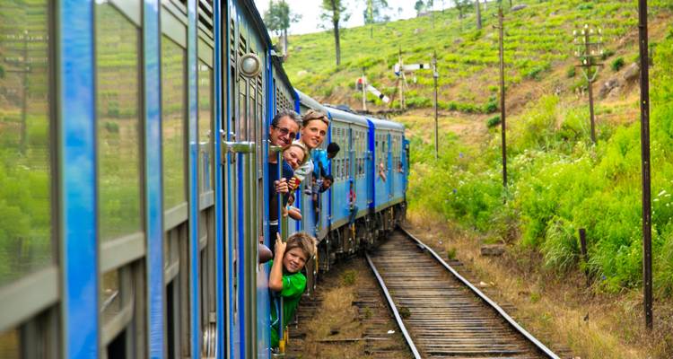 Zug fährt durch eine malerische Landschaft mit Menschen, die hinausschauen.