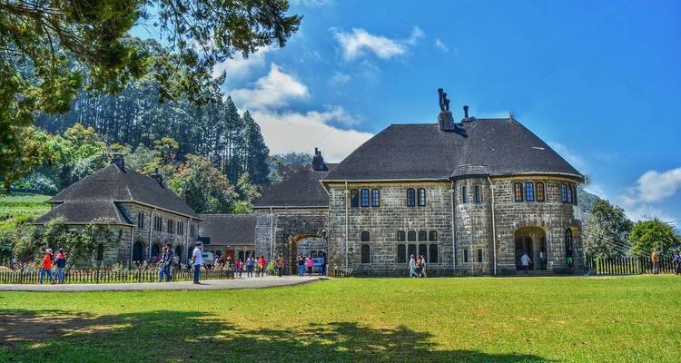 Historisches Gebäude, umgeben von Menschen und Grün.