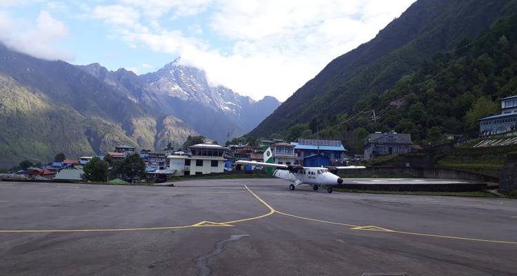 Landingsbaan met een klein vliegtuig en bergachtig landschap.