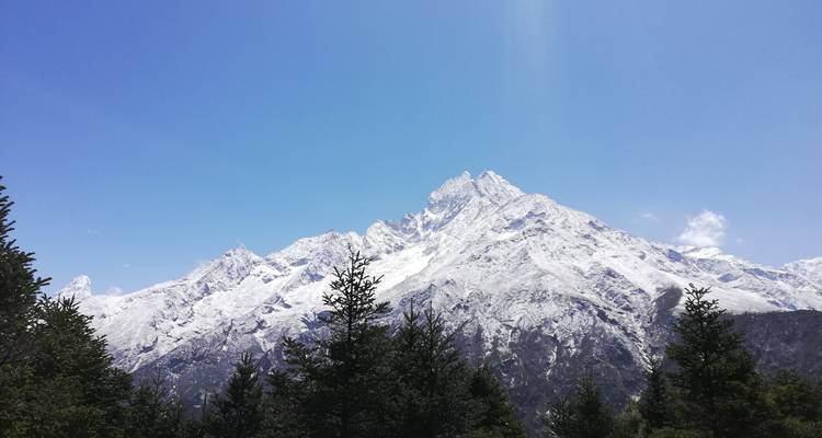 Besneeuwde bergtop onder een strakblauwe hemel.