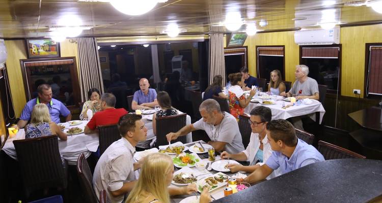 Personas cenando en el interior en múltiples mesas, disfrutando de una comida juntas.
