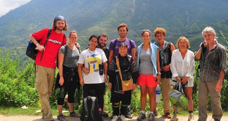 Grupo de excursionistas posando en un paisaje exuberante con colinas.