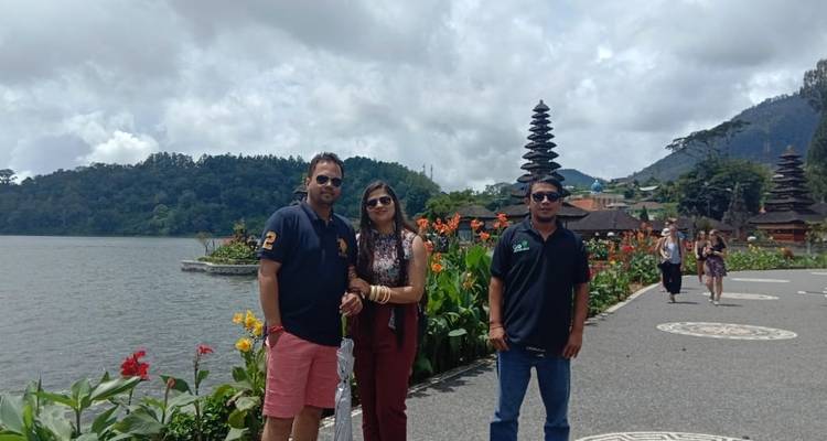 Grupo posando con un templo junto al lago de fondo en medio de un paisaje exuberante.