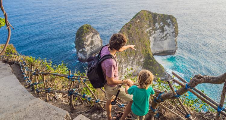 Padre e hijo admirando una formación rocosa costera.