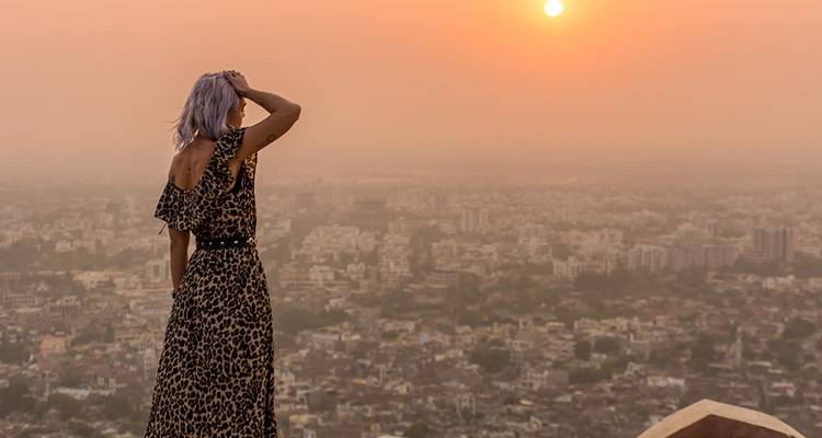 Frau mit Blick auf eine Stadtlandschaft bei Sonnenuntergang