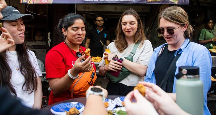 Reisende probieren frittierte Straßensnacks von blauen Tellern an einem lebhaften Marktstand.