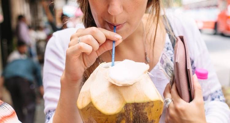 Nahaufnahme einer Frau, die aus einer Kokosnuss trinkt.