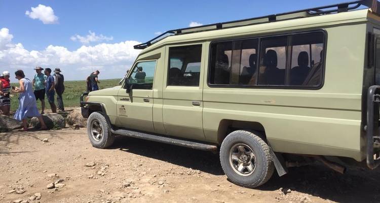 Safari voertuig met toeristen op ruw terrein.